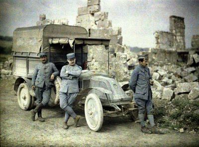 Three French soldiers stand with their truck in front of a heavily damaged building in Aisne
