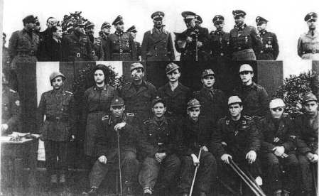 29. Waffen Grenadier Division der SS (italienische Nr. 1)
Italský ministr obrany a velitel Ligurské armády maršál Graziani hovoří ke zraněným z 29. SS Division. Vojáci nosí zajímavé varianty uniforem jako černé košile, armádní orlice. Žena je italská SAAF (sbor fašistických sester) sloužící u divize. Na tribuně jsou v pozadí generálové SS Wolf a Rauff (HSSPF, severní Itálie), po pravici Grazianiho je SS-Obersturmbannführer Deglioddi, druhý je SS-Oberführer Max Hansen, velitel divize.
Klíčová slova: waffen-ss